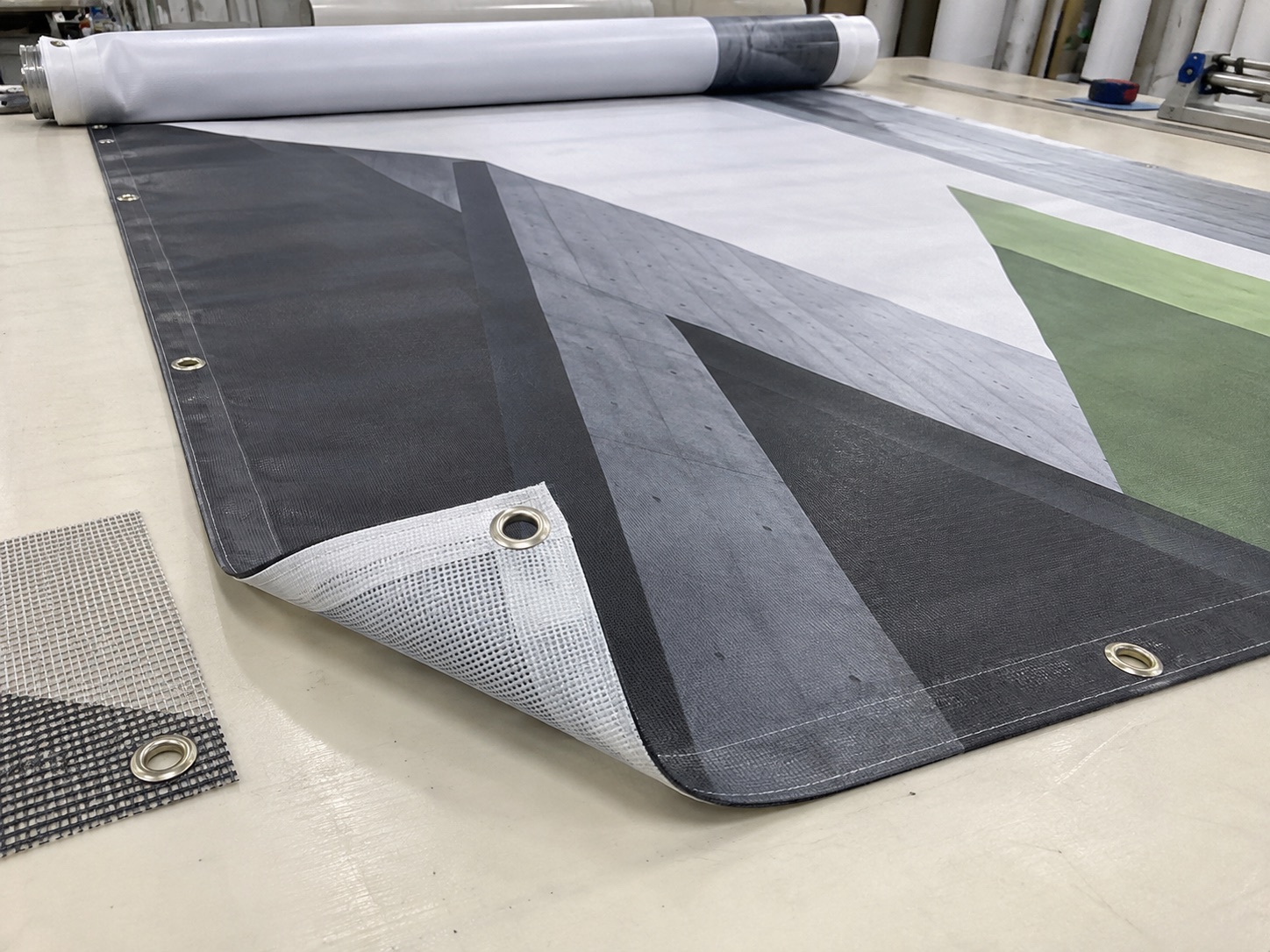 Bedrucktes PVC-Werbebanner mit Saum und Metallösen sowie ein Mesh-Muster